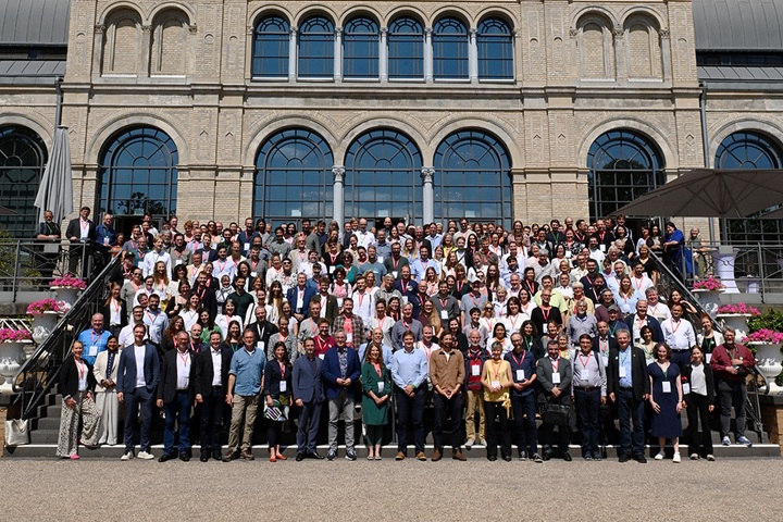 Big group of conference participants posing for photo on stairs