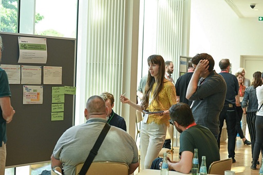 People standing in front of pinboard talking at CAIC25