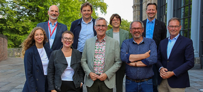 Group photo of nine people, men and women, looking into the camera